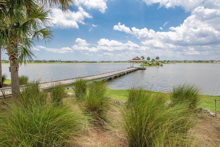 Lakeside view with a long dock, covered gazebo, and ornamental grasses in the foreground.