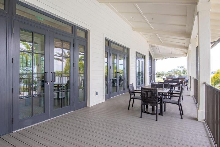 Covered patio with gray plank flooring, dark-framed glass doors, and an outdoor dining set.