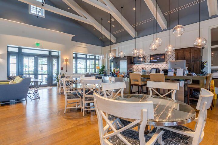Open-plan kitchen and dining area with exposed ceiling beams, glass pendants, and hardwood floors.