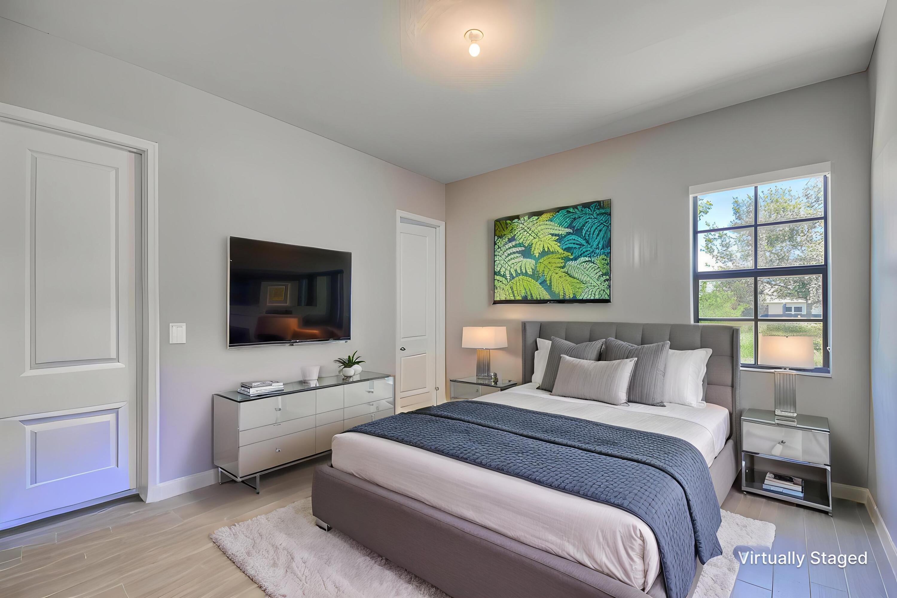 Bedroom with blue-and-white bedding, a gray headboard, and a window overlooking greenery.