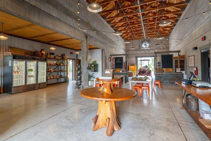 Spacious rustic interior with exposed timber trusses, concrete floors, and wooden tables.
