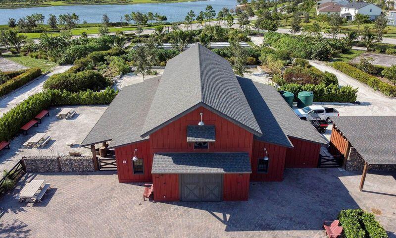Red barn-style building with a gray roof, paved grounds, and water visible beyond.