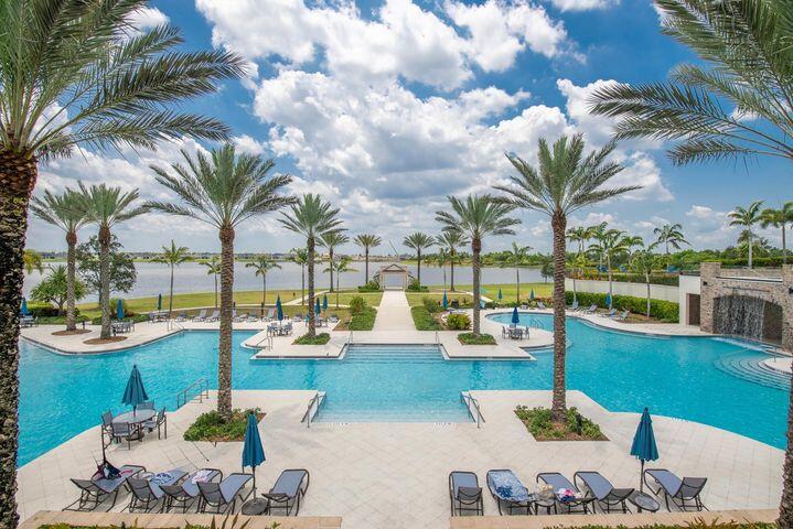 Large palm-lined pool with lounge chairs and a central walkway