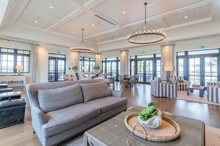 Living room with gray sofas, tall windows, and two circular chandeliers beneath a coffered ceiling.