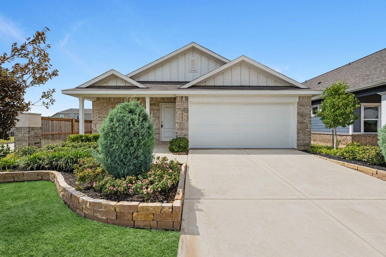 Single-story home with brick accents, a two-car garage, and landscaped flower beds.