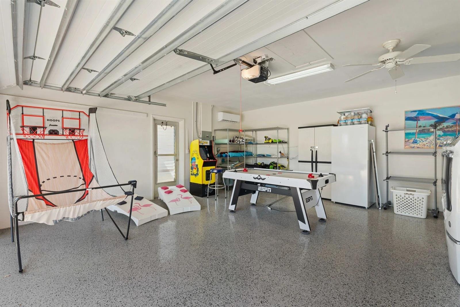 Garage recreation area with a foosball table, basketball arcade game, and storage shelves.