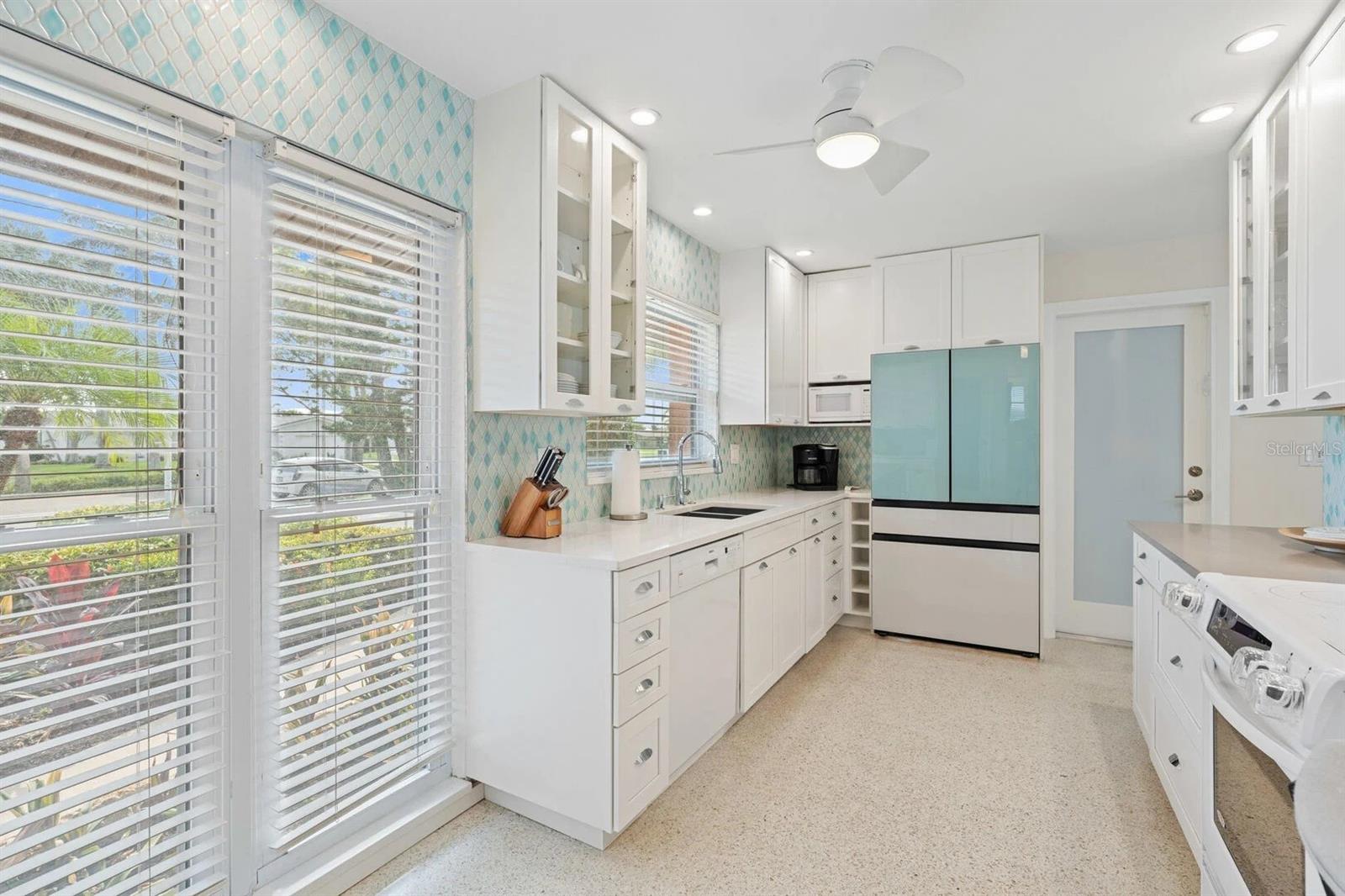 Bright white kitchen with aqua tile backsplash and a distinctive pale turquoise refrigerator.