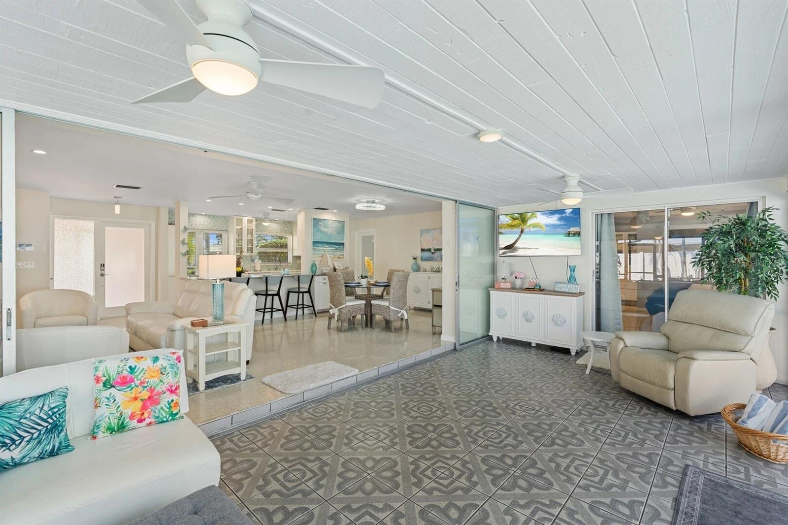 Furnished lanai with patterned tile floors, a ceiling fan, and sliding doors opening to the living area.