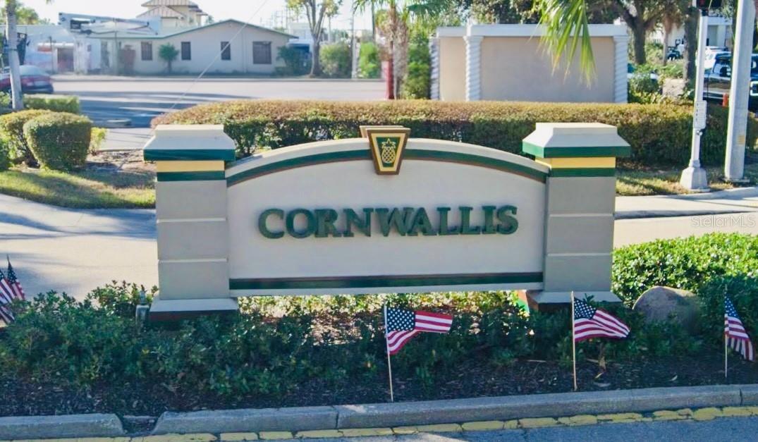 Cornwallis entrance sign with green and gold trim and small American flags.