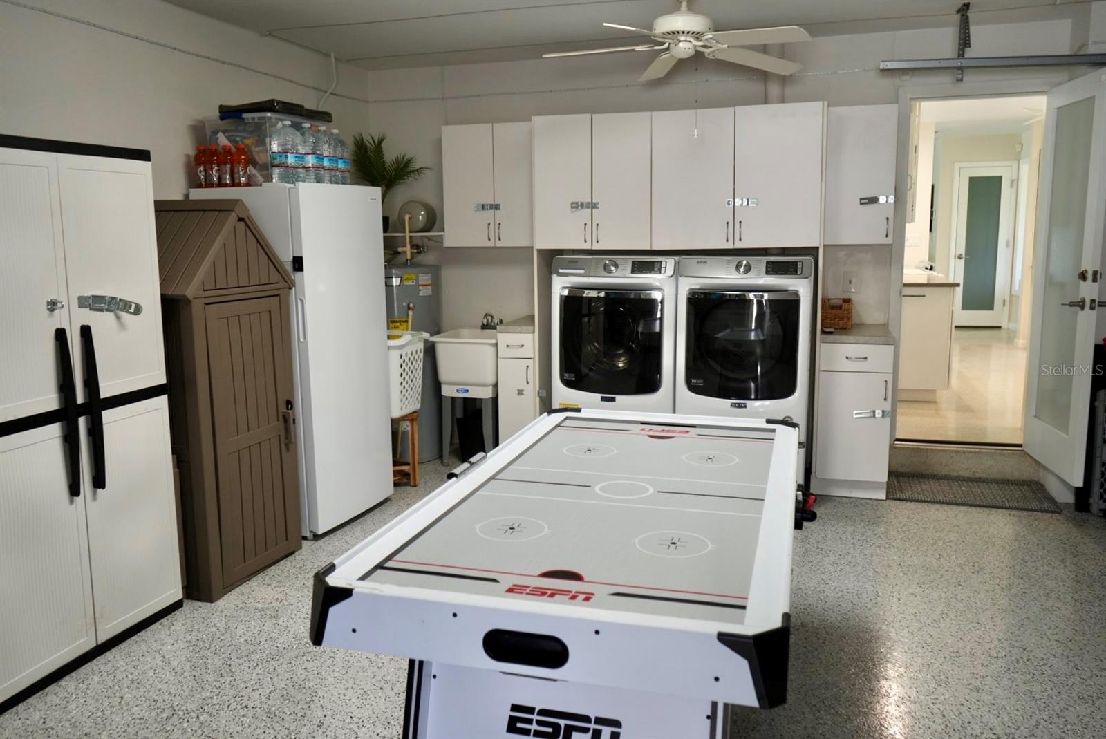Garage laundry area with white cabinets, washer and dryer, and an air hockey table.