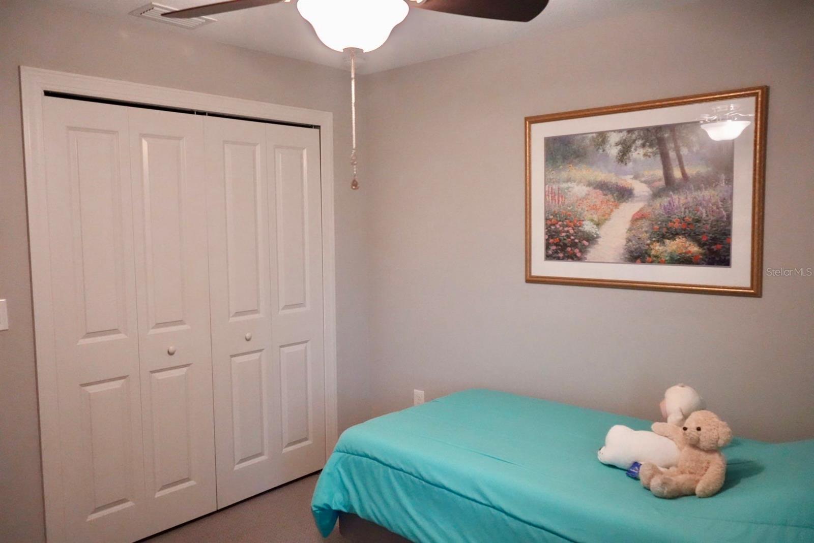 Bedroom with a turquoise bed, white closet doors, and framed floral artwork.