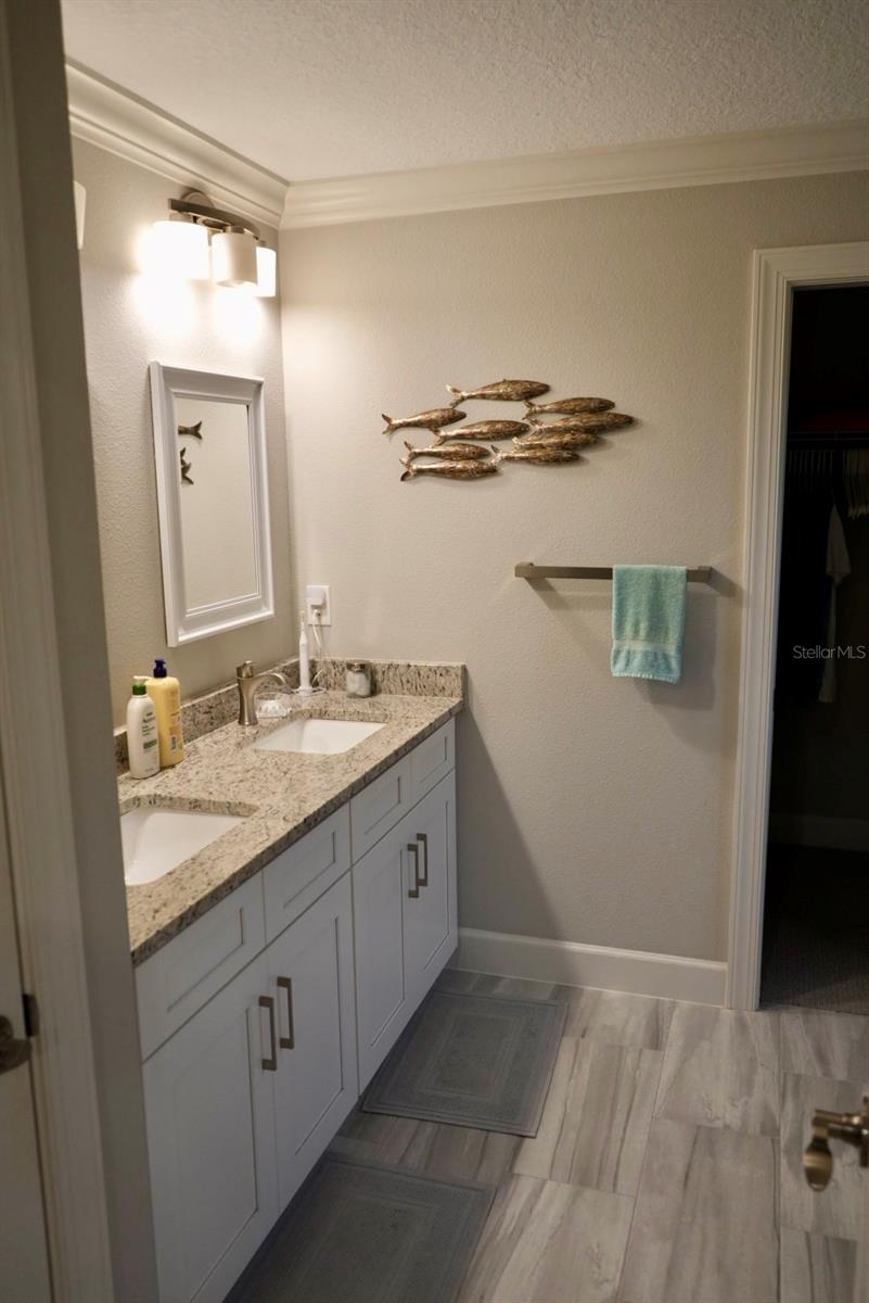 Bathroom with a white double vanity, granite countertop, framed mirror, and fish wall decor.