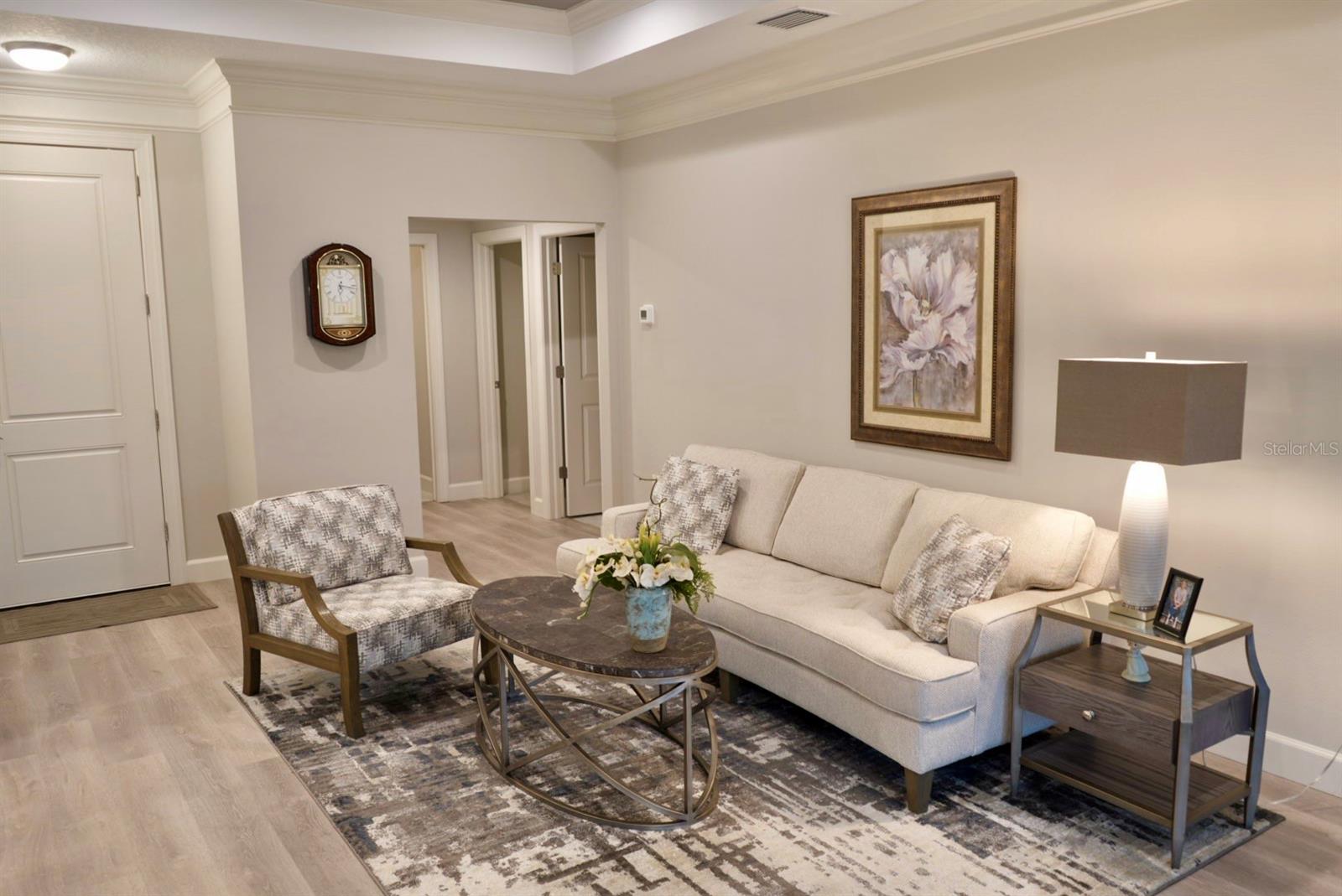 Furnished living room with a cream sofa, patterned chair, round coffee table, and large area rug.