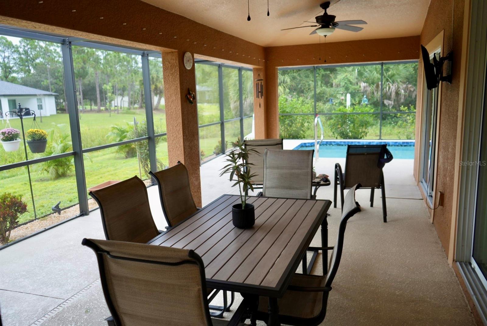 Screened lanai with outdoor dining furniture and a swimming pool.