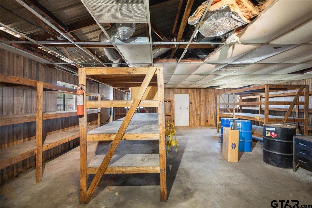 Storage room with wooden shelving, barrels, and an exposed ceiling.