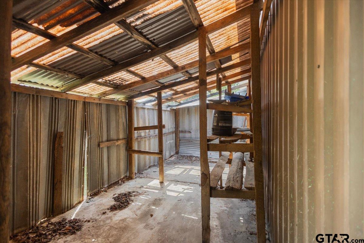 Metal-sided storage shed interior with exposed wooden supports and corrugated roofing.