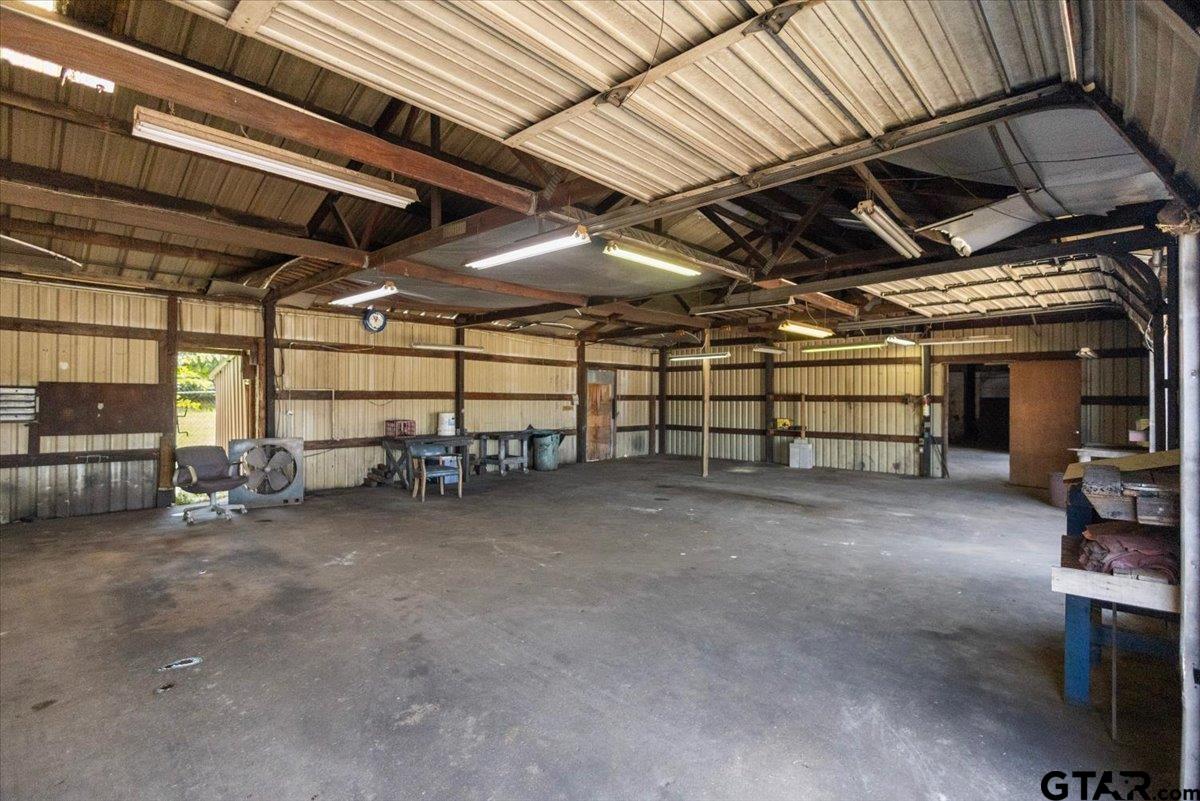 Large metal workshop with a high exposed-beam roof, concrete floor, and workbenches.
