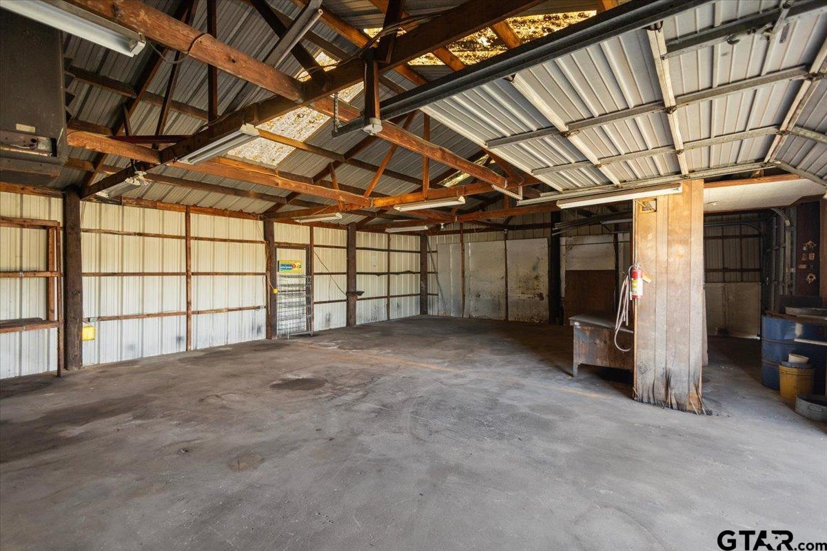 Large garage with a concrete floor, exposed timber trusses, and corrugated metal walls.