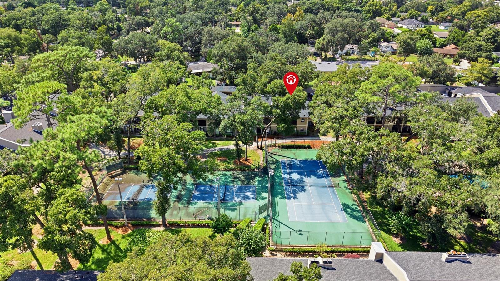 Aerial view of a tree-lined residential community with multiple tennis courts.