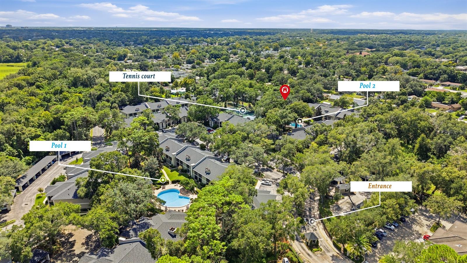Aerial view of a residential community with two pools, a tennis court, and a labeled entrance.