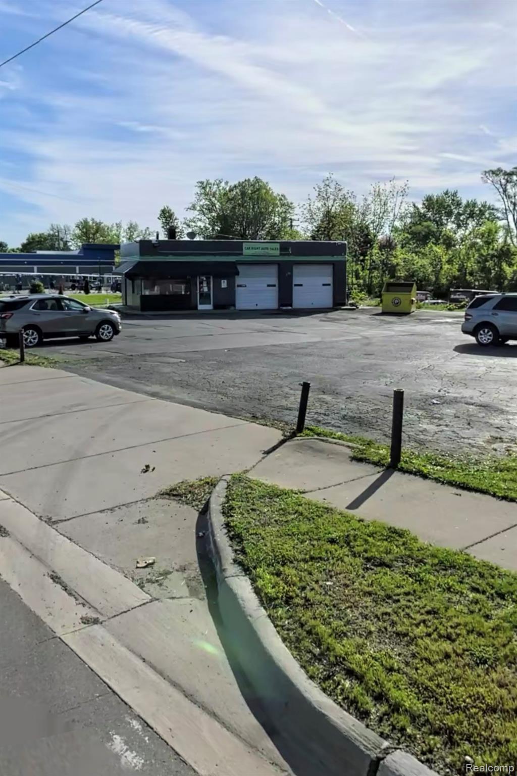 Small commercial garage with two service-bay doors and a paved parking lot.