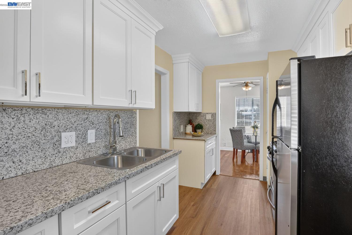 Kitchen with white cabinets, speckled granite counters, a double sink, and stainless-steel appliances.