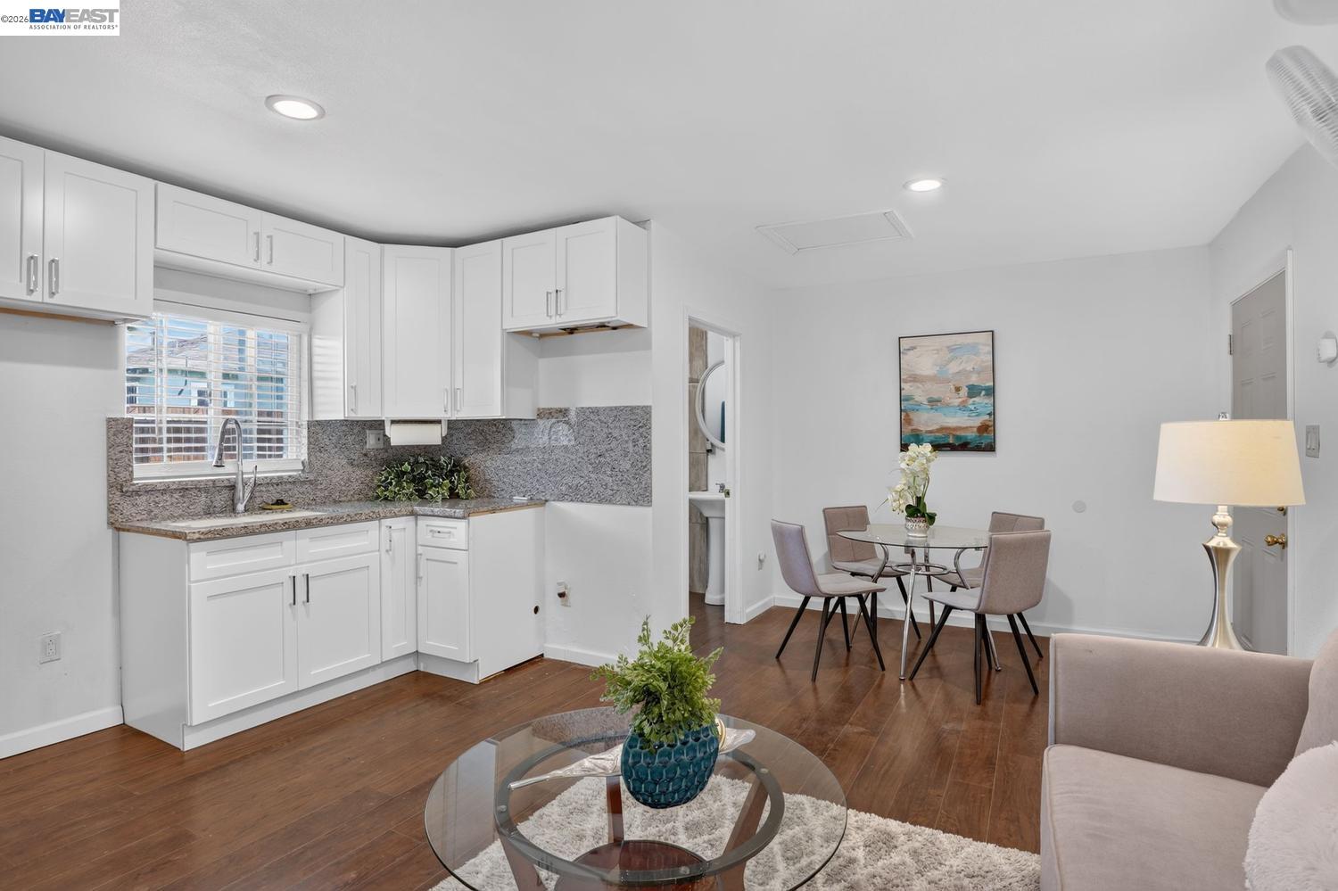 Kitchen and dining area with white cabinets, granite counters, and a glass table.