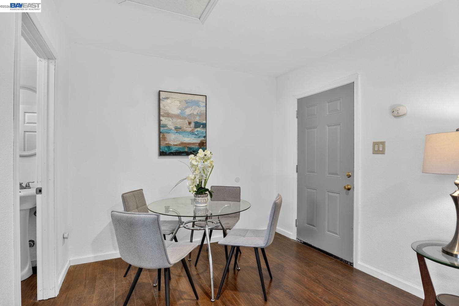 Dining area with a glass table, gray chairs, orchid centerpiece, and gray front door.