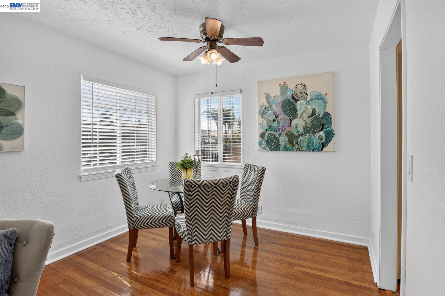 Dining area with chevron-patterned chairs, polished hardwood floors, and cactus wall art.