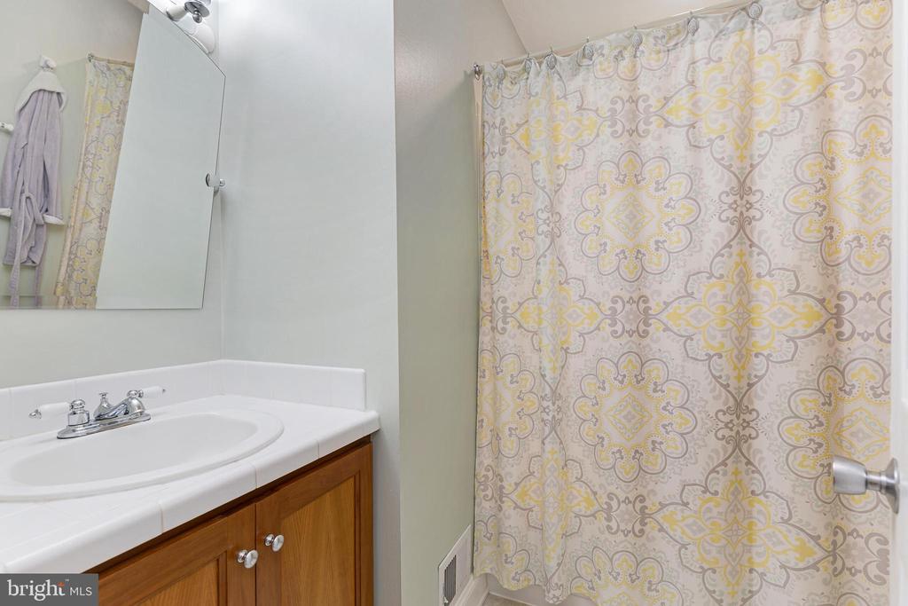 Bathroom vanity with a mirrored cabinet beside a yellow-and-gray patterned shower curtain.