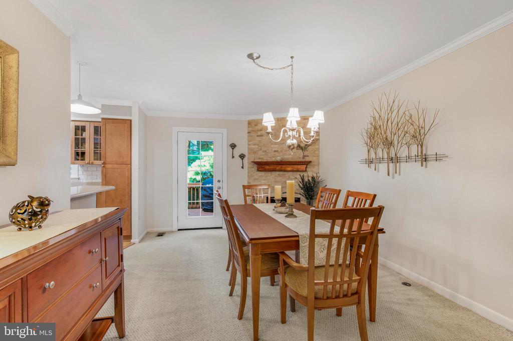 Dining room with a wooden table, chandelier, and stone fireplace beside a glass-paneled door.