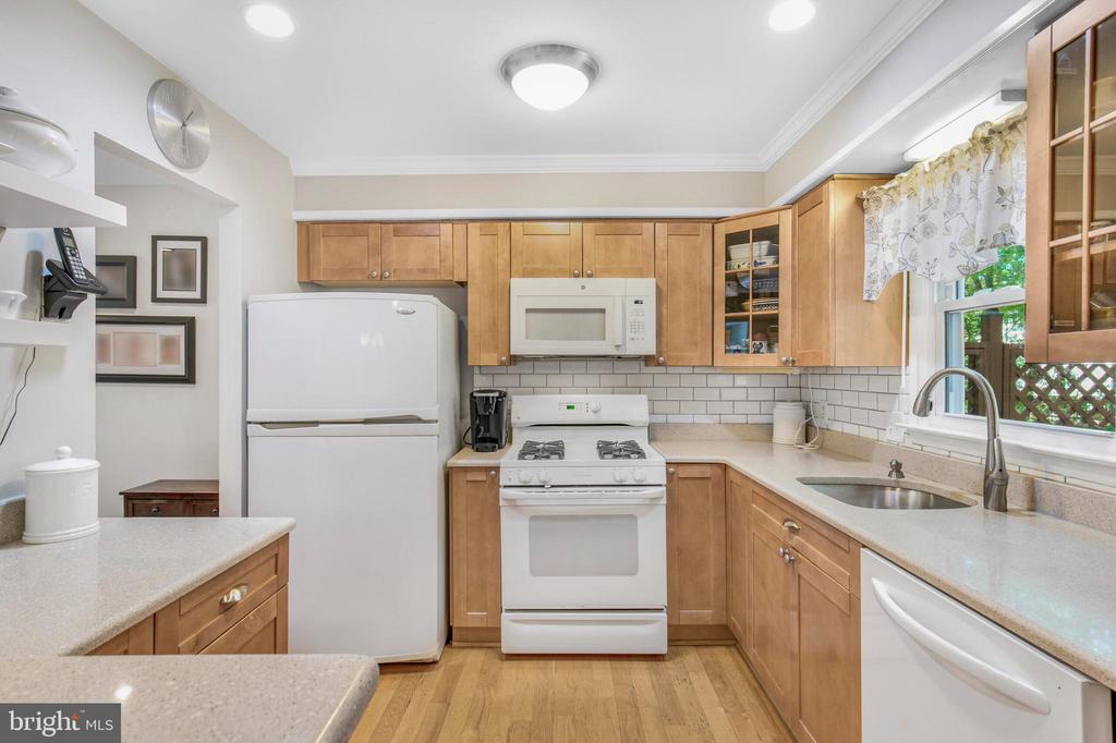 Kitchen with wood cabinets, white appliances, subway tile backsplash, and a window over the sink.