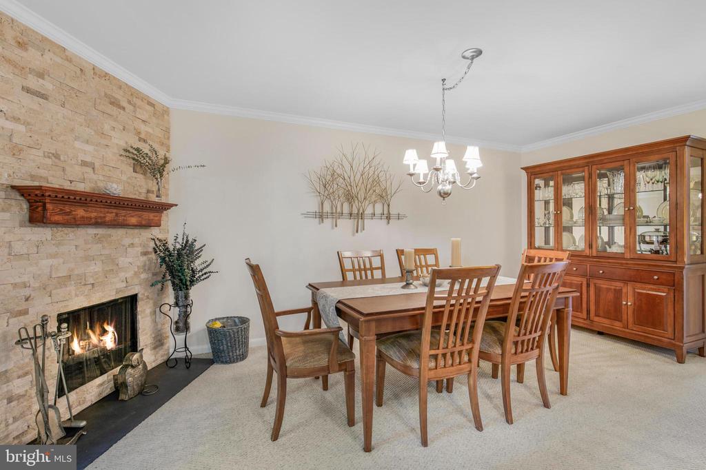 Furnished dining room with a stone fireplace, wooden dining set, and glass-front china cabinet.