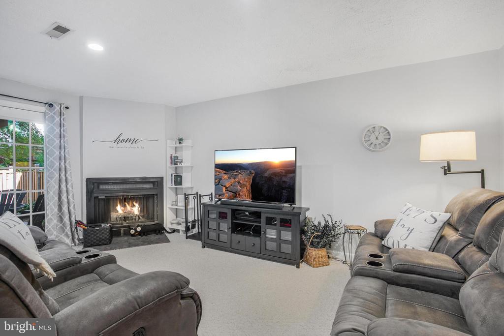 Living room with gray reclining sofas, a lit fireplace, and a television on a media console.