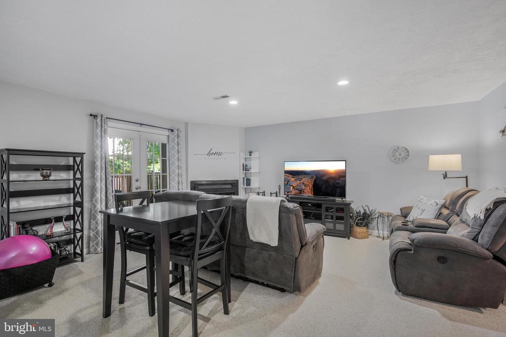 Furnished living room with gray sectional, dining table, fireplace, and glass patio doors.