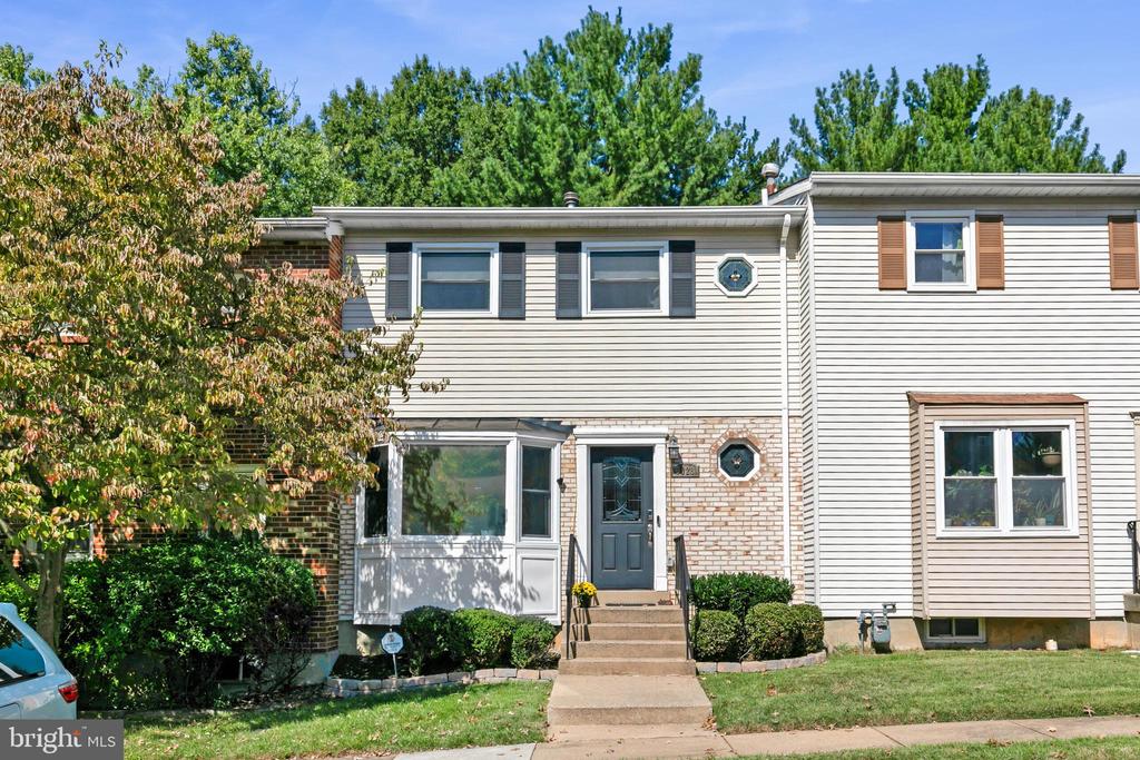 Two-story attached home with a bay window, brick accents, and steps to the front entrance.