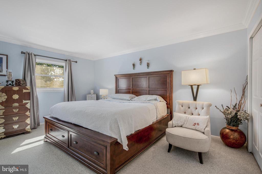 Bedroom with a dark wood storage bed, pale blue walls, and a gray chair beside the bed.