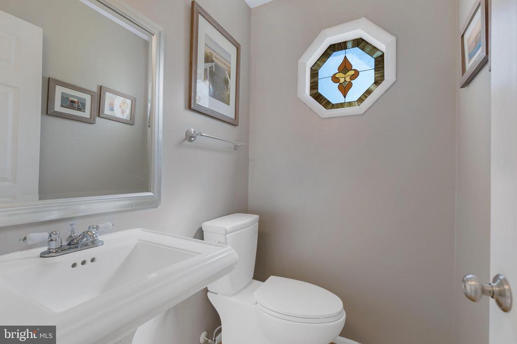 Bathroom with a white pedestal sink, toilet, and octagonal stained-glass window.