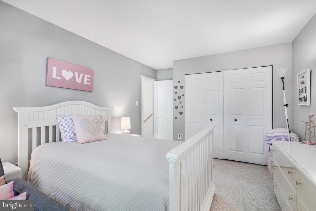 Bedroom with a white bed, gray walls, pink accents, and double closet doors.