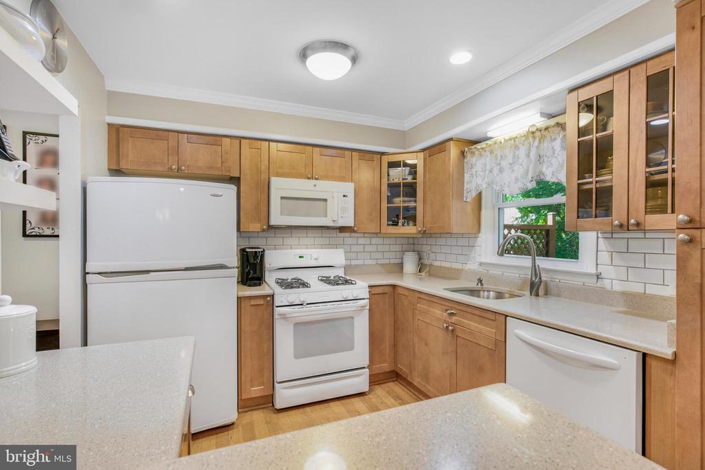 Kitchen with honey-toned cabinets, white appliances, subway-tile backsplash, and a peninsula.