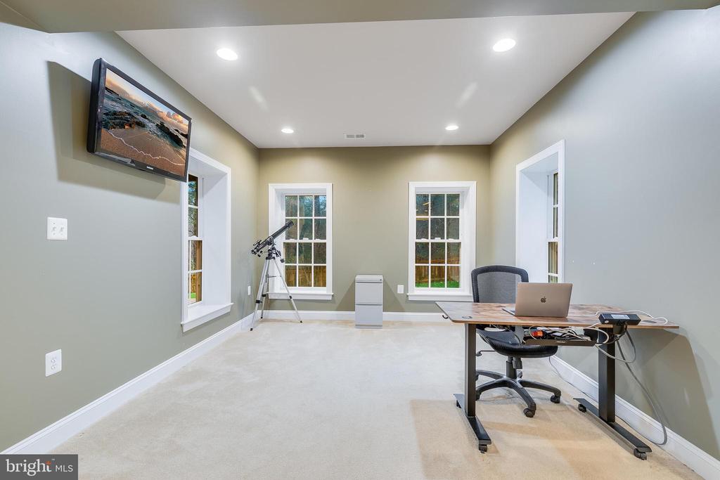 Furnished home office with a desk, telescope, and three windows.