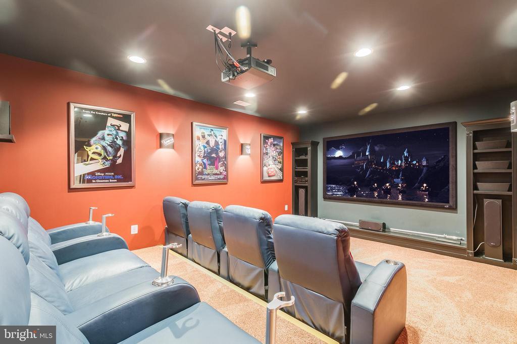 Home theater with blue leather recliners, a large screen, and framed movie posters.