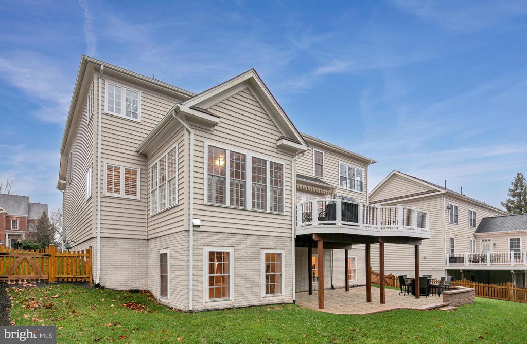 Rear exterior of a beige two-story home with a raised deck and covered patio.