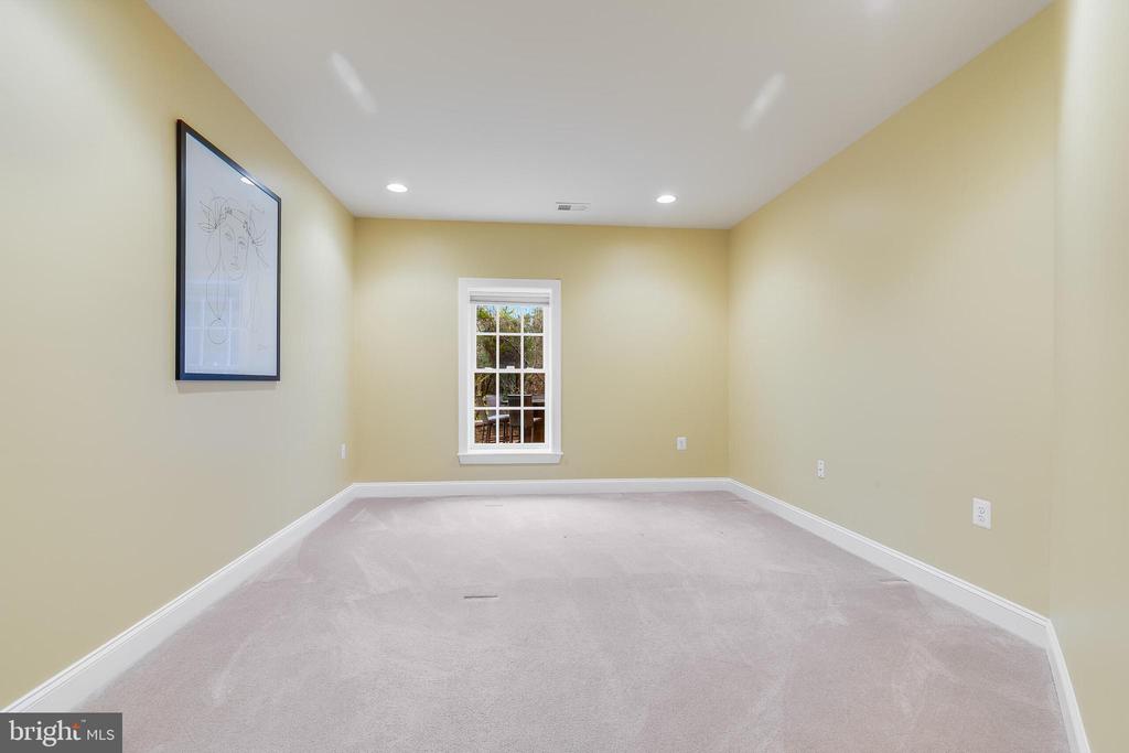 Empty carpeted room with pale yellow walls, a single window, and framed artwork.
