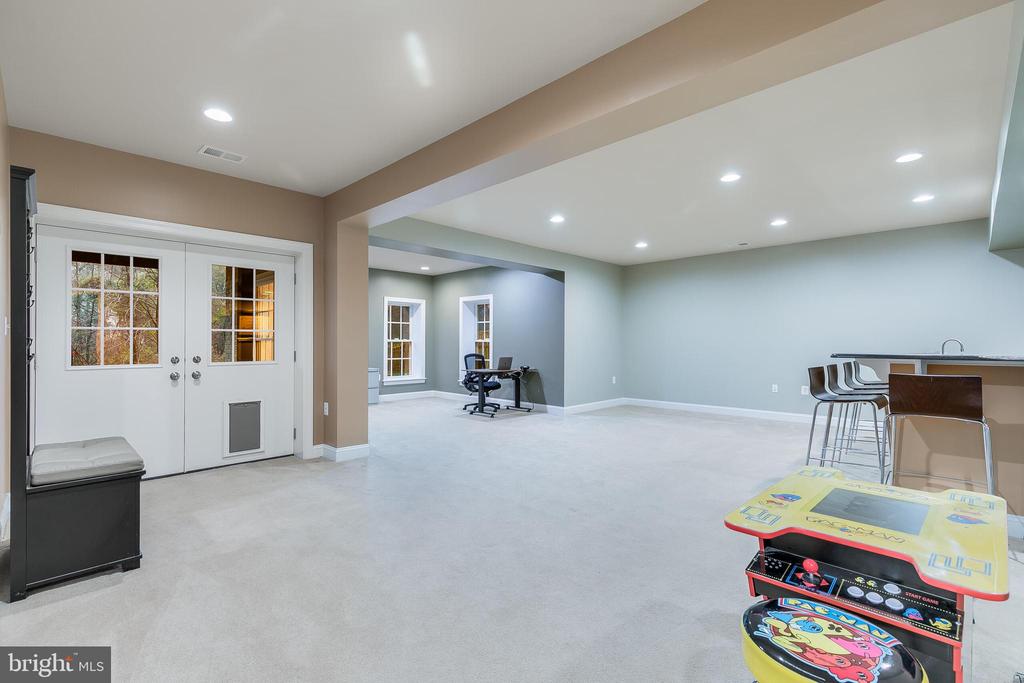 Finished basement recreation room with an office nook, bar seating, and an arcade game.
