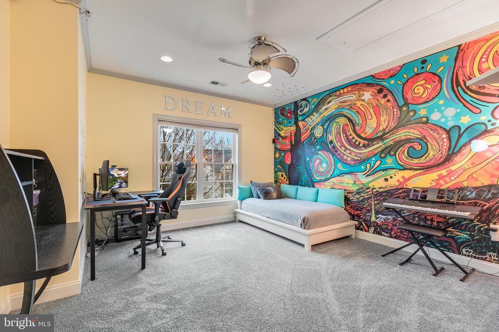 Bedroom with a vivid mural, gray bed, desk, and keyboard.