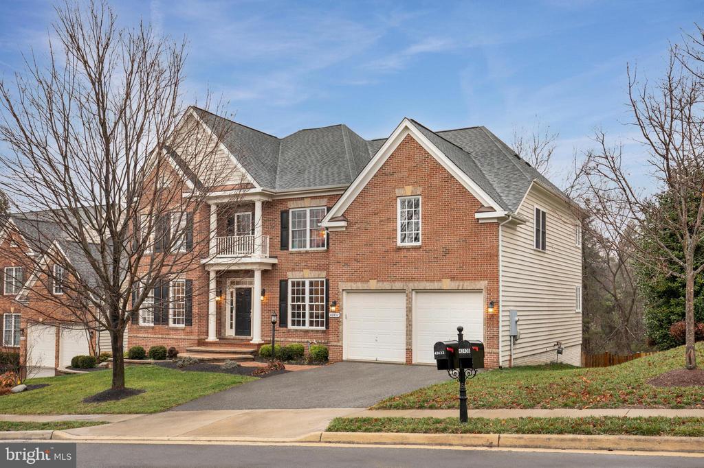 Two-story brick house with a small balcony, attached double garage, and bare trees.