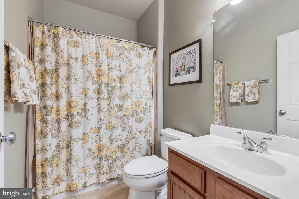 Bathroom with a floral shower curtain, white toilet, and wood vanity.