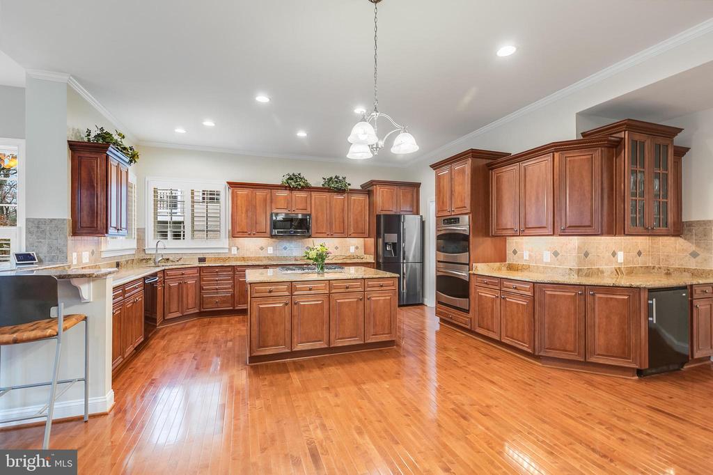 Spacious kitchen with cherry cabinets, a central island, granite counters, and hardwood floors.