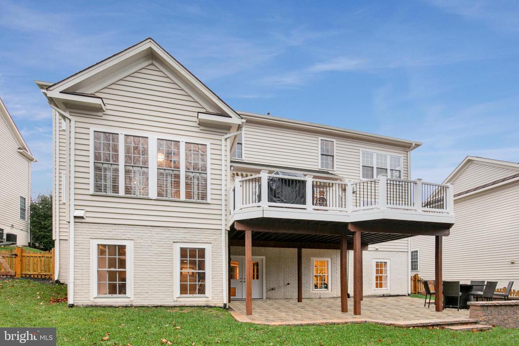 Rear of a beige-sided house with a raised deck and covered patio.